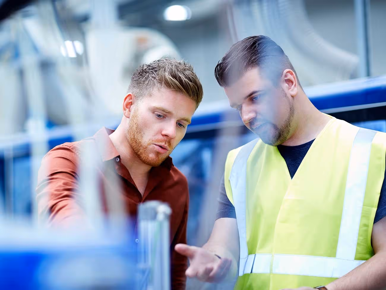 Zwei Männer betrachten und diskutieren gemeinsam einen technischen Plan.